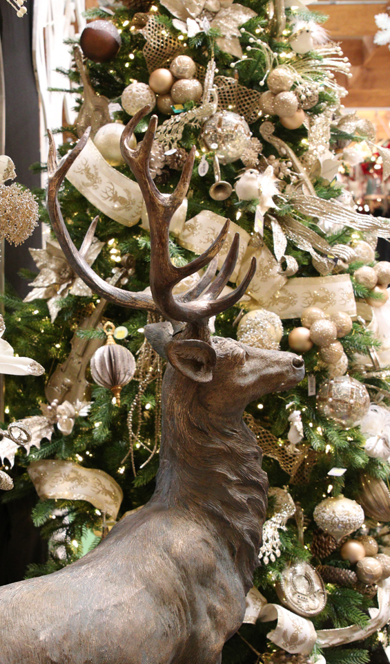 Artificial Christmas tree decked out in white and gold, with a large standing reindeer figurine